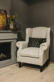 Crèmekleurige fauteuil bij de open haard