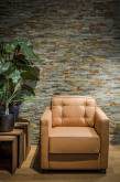 Single cognac-coloured armchair in front of natural stone