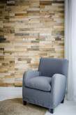 Light grey upholstered armchair in front of a wooden slat wall