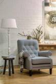 Grijze gestoffeerde fauteuil voor een bakstenen muur